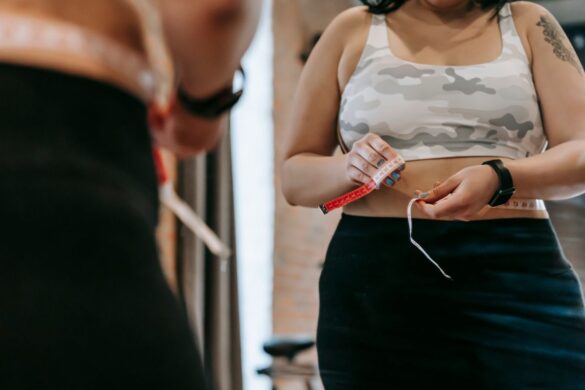 Woman using a tape measure to measure herself in front of a mirror at home