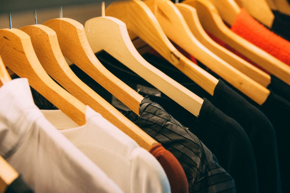 Row of clothes on wooden hangers, various fabrics