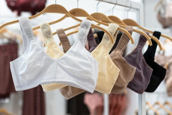 Assorted bras displayed on wooden hangers in soft light